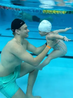 Antrenor SwimLab ținând un bebeluș în apă, la o ședință de acomodare