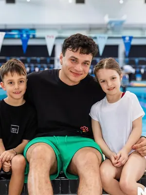 Antrenorul SwimLab alături de doi copii, așezați pe blocstart